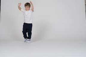 Front view of a boy jumping excitedly with hands up in the air