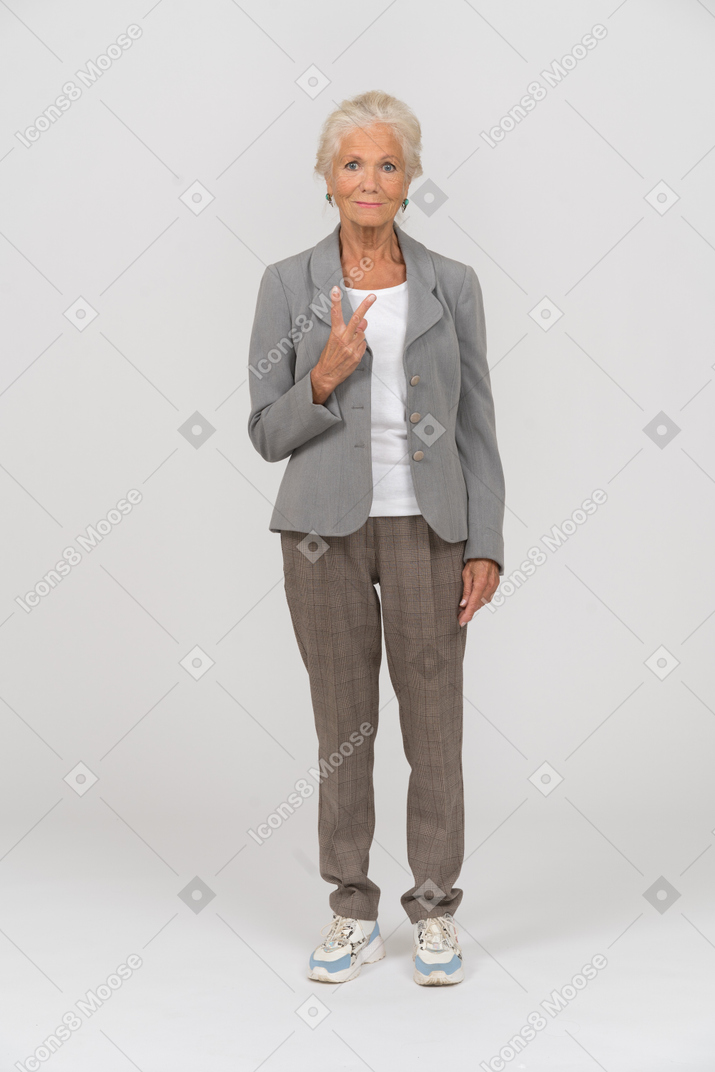 Front view of an old lady in suit showing v sign