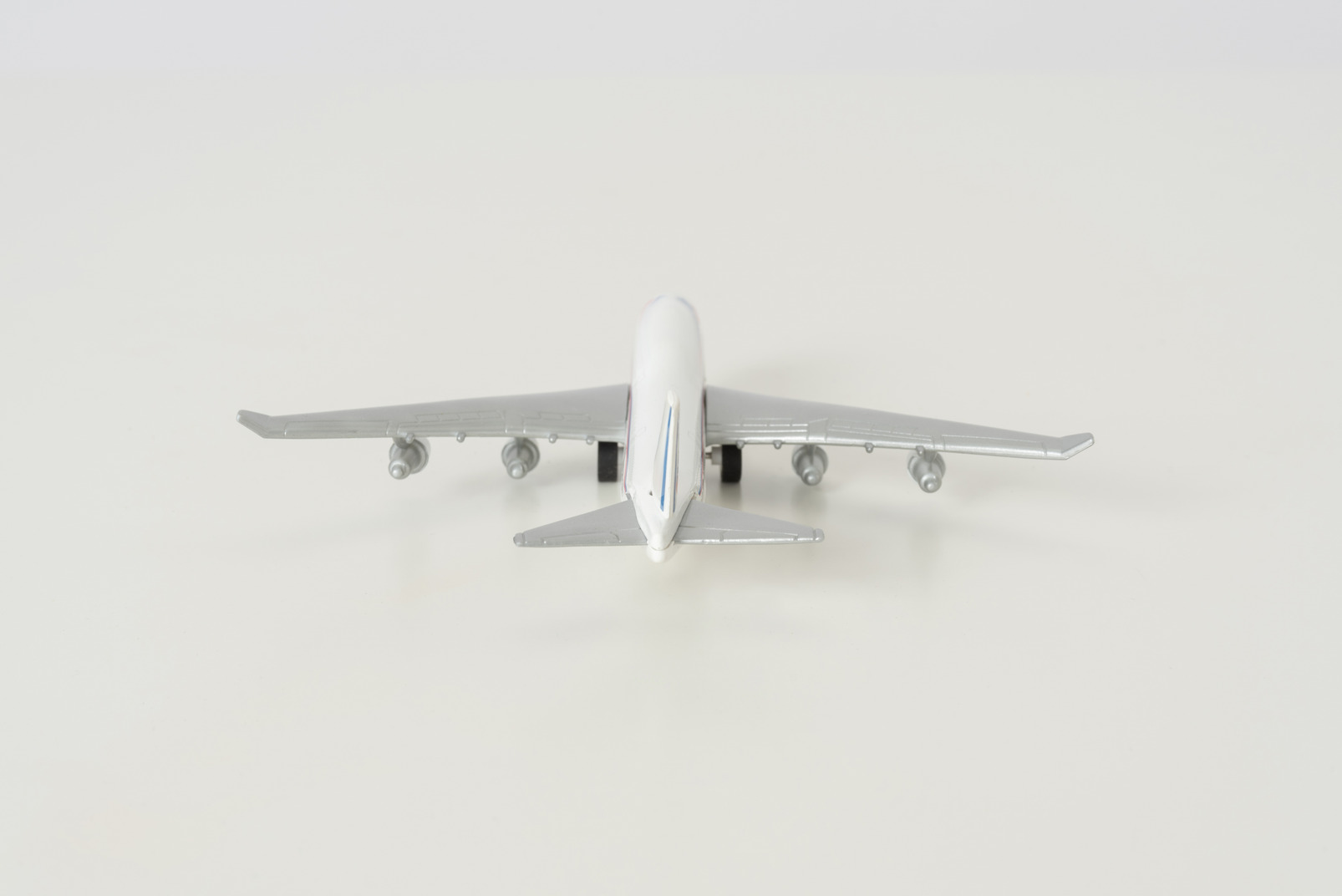 Toy airplane photographed from the back on grey background