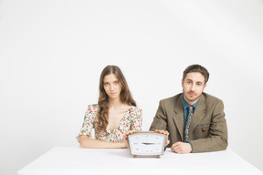 Couple sitting at the table and holding a clock