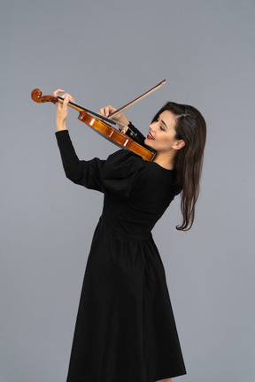 Close-up de uma jovem alegre de vestido preto tocando violino