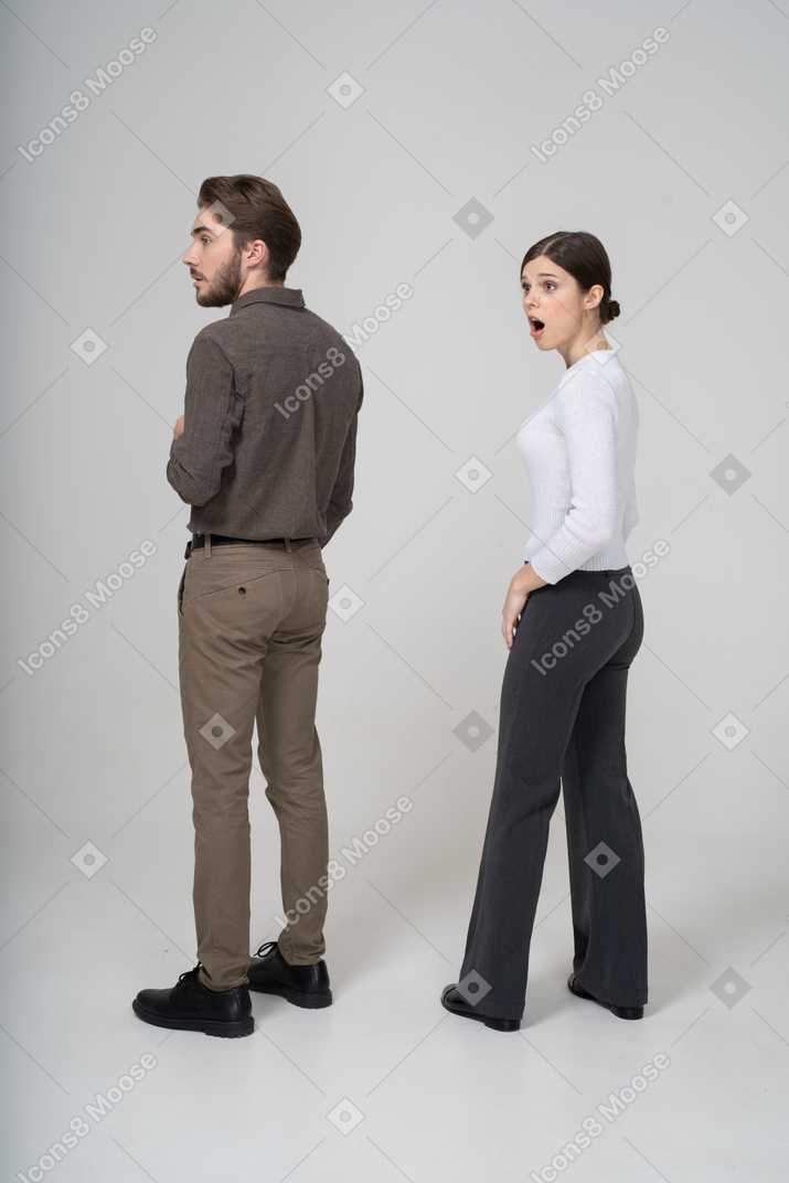 Шокированная молодая пара в офисной одежде, вид сзади в три четверти