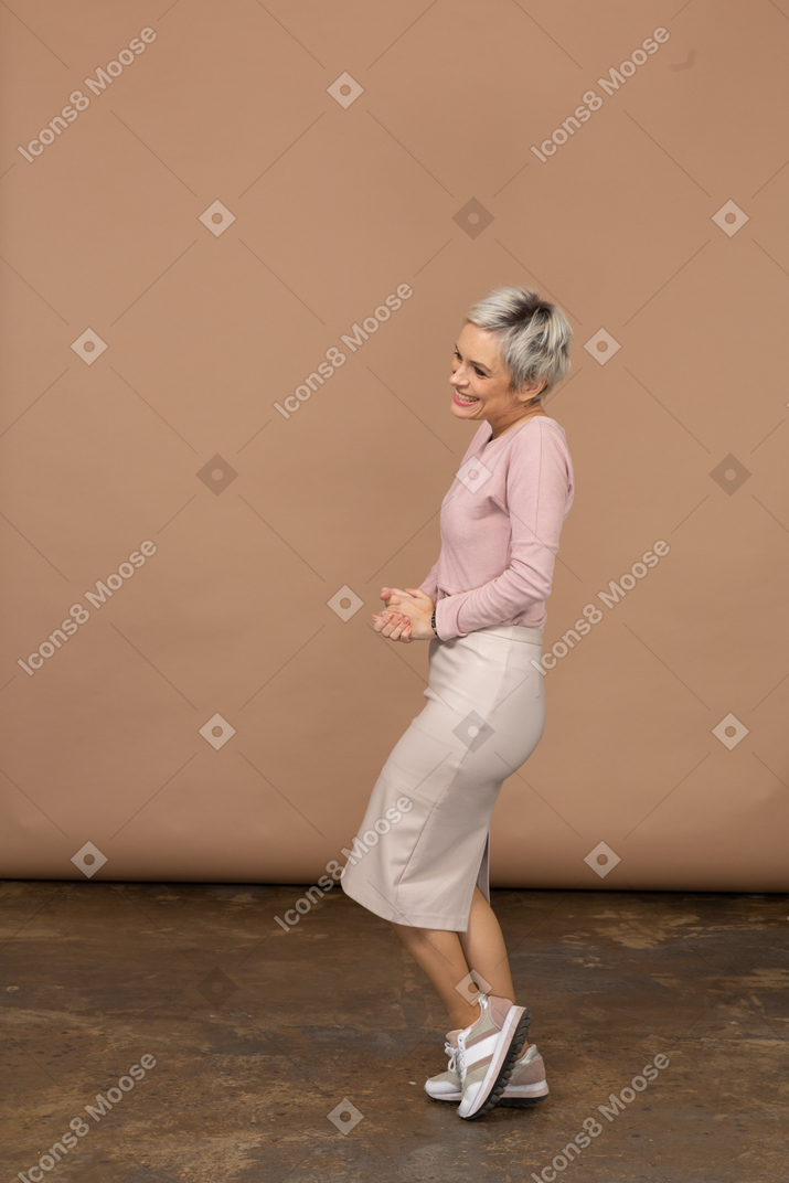 한쪽 다리에 포즈를 취하는 캐주얼 옷을 입은 행복한 여성의 측면