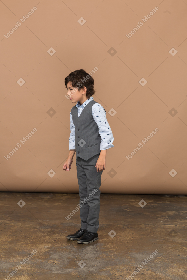 Side view of a boy in grey suit looking at something with interest