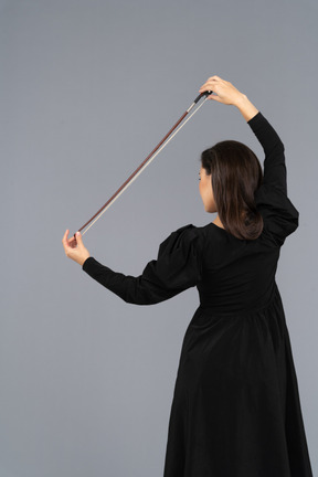 Vista posteriore di una giovane donna in abito nero che tiene il fiocco