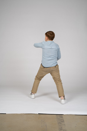 Back view of a boy standing in blue shirt