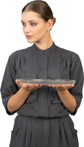 Front view of a young woman in a jumpsuit holding glass plate