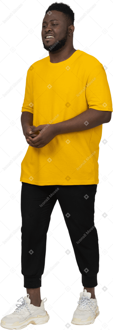 Three-quarter view of a young dark-skinned man in yellow t-shirt holding hands together