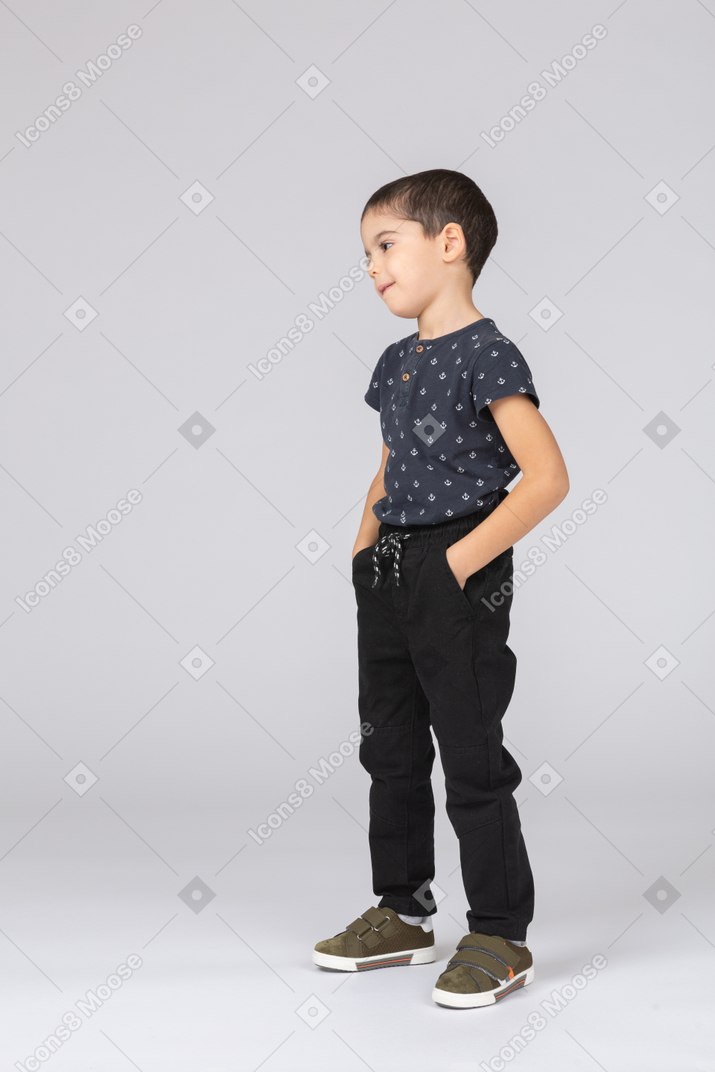 一个可爱男孩的侧视图，双手插在口袋里