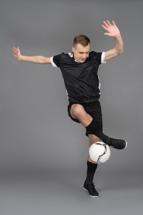 Vista frontal de un jugador de fútbol masculino levantando las manos y haciendo un truco