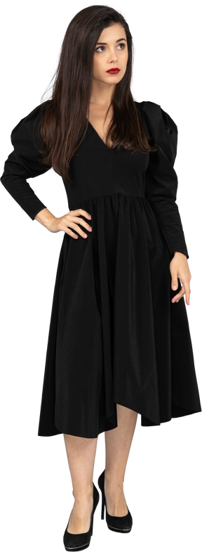 Vista frontale di una giovane donna in un abito nero, mettendo la mano sul fianco