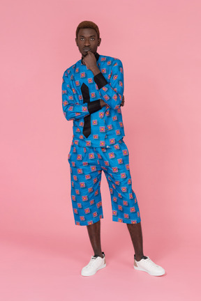 Black man in blue pajamas standing on pink background