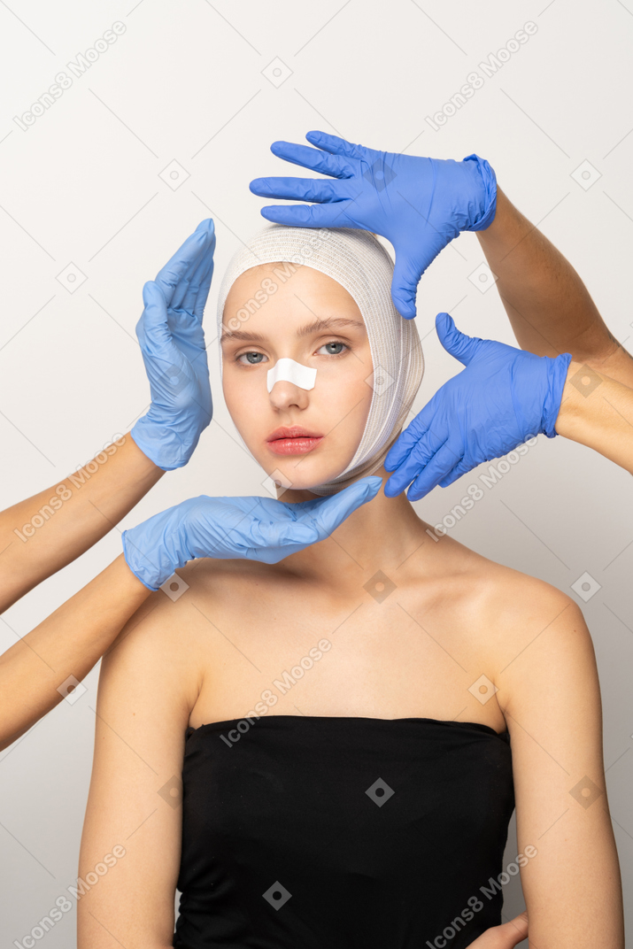 머리에 붕대를 감고 손으로 얼굴을 감싸고 있는 젊은 여성