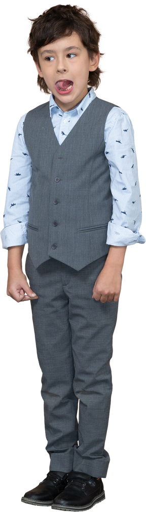 Вид спереди симпатичного мальчика в сером костюме, смотрящего в камеру и показывающего язык