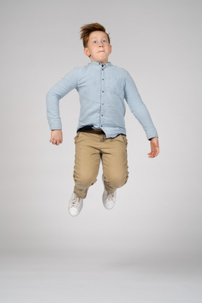 A boy jumping high with bent knees