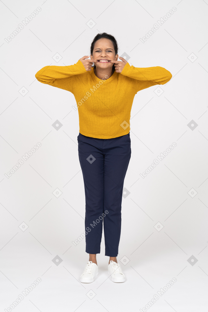 Vista frontal de uma garota com roupas casuais colocando os dedos na boca