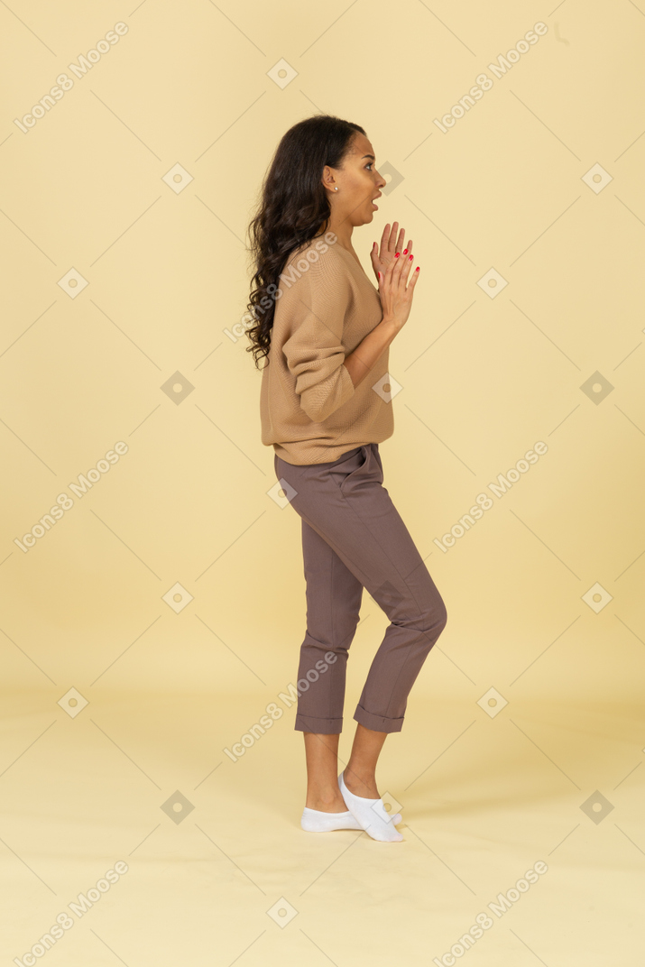 Vista laterale di una giovane femmina senza parole dalla carnagione scura, alzando le mani