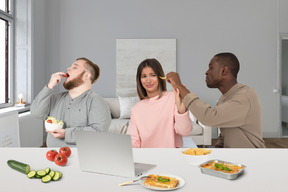 Amigos sentados a la mesa y comiendo bocadillos saludables y no saludables
