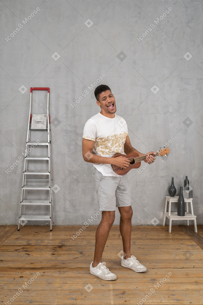 Three-quarter view of a man singing and playing ukulele