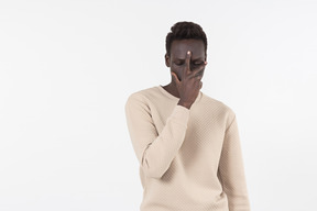 A young black man in a grey sweater standing alone on the white background