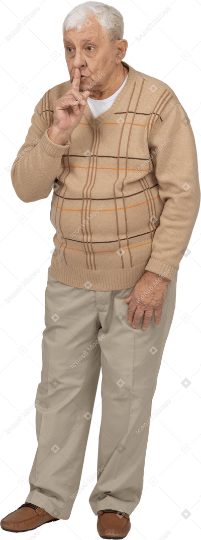 Front view of an old man in casual clothes showing silence sign