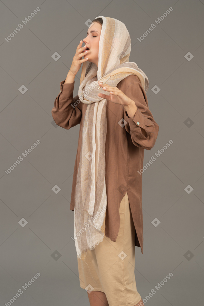 Young woman in headscarf smoking a cigarette and coughing