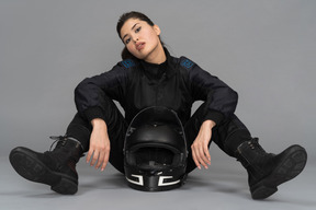 A self-confident young woman sitting with a helmet between her legs