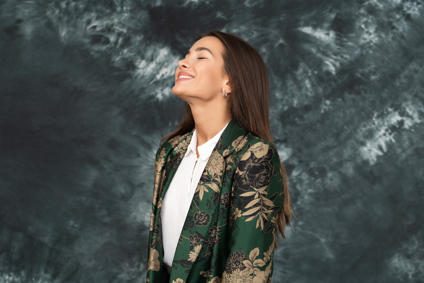 Three-quarter view of a woman in green japanese jacket smiling widely with her eyes closed