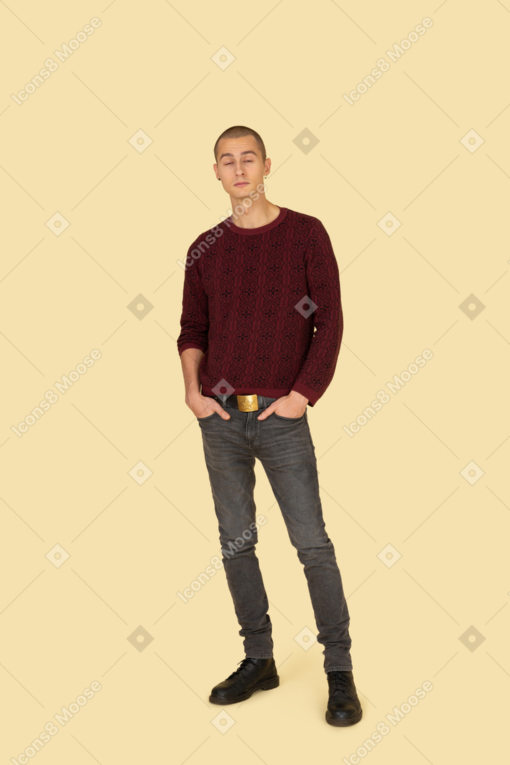一个年轻的男性，穿着休闲服把手放在口袋里的前视图