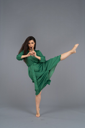 Front view of a dancing young lady in green dress playing flute