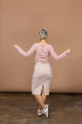 Vista traseira de uma mulher com roupas casuais mostrando os polegares para cima