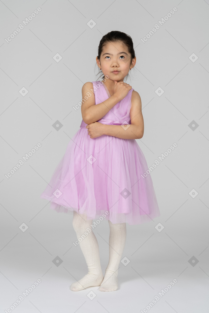 Little girl in pink dress standing and rolling eyes