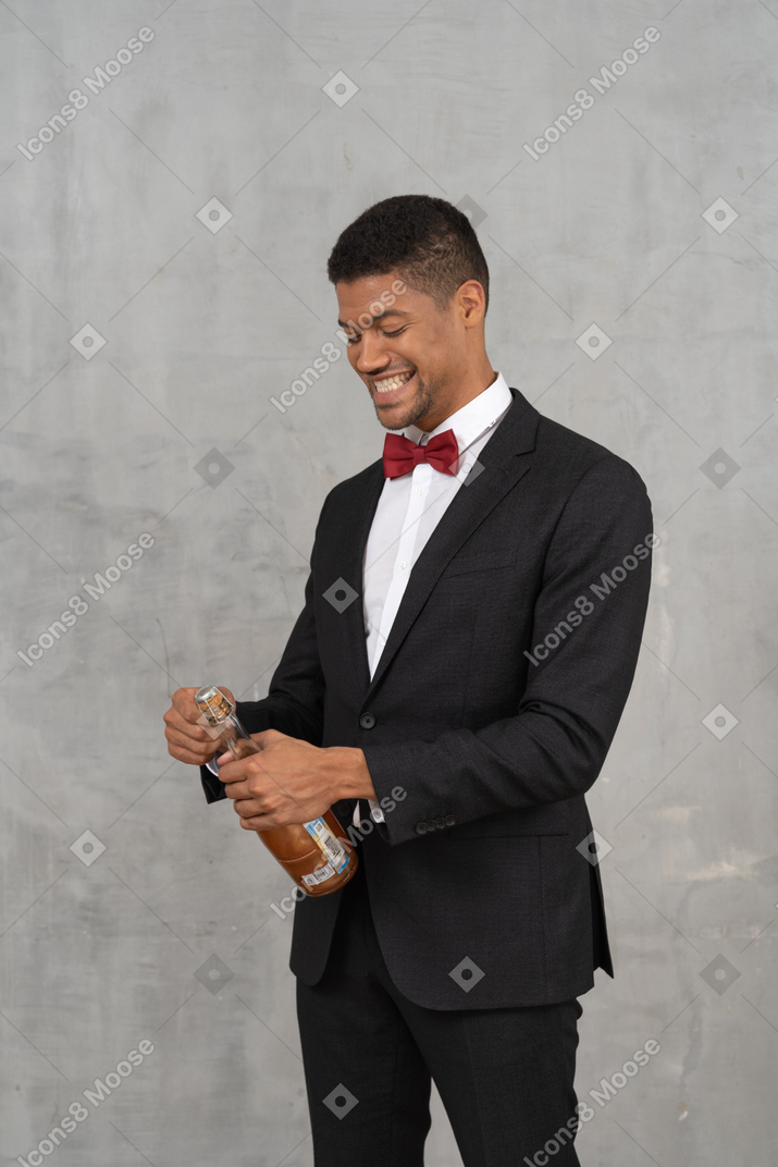 Hombre abriendo una botella de champán y sonriendo ampliamente