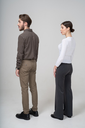 Vista traseira de três quartos de um jovem casal com roupas de escritório, mostrando a língua