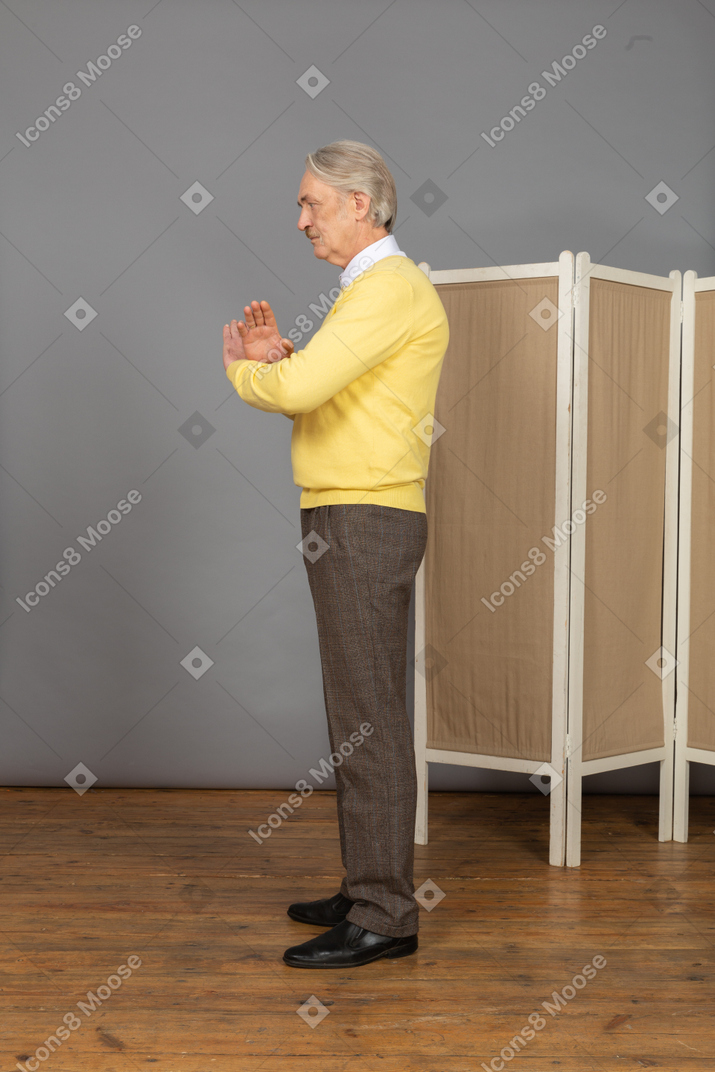 Side view of an unwilling old man crossing hands
