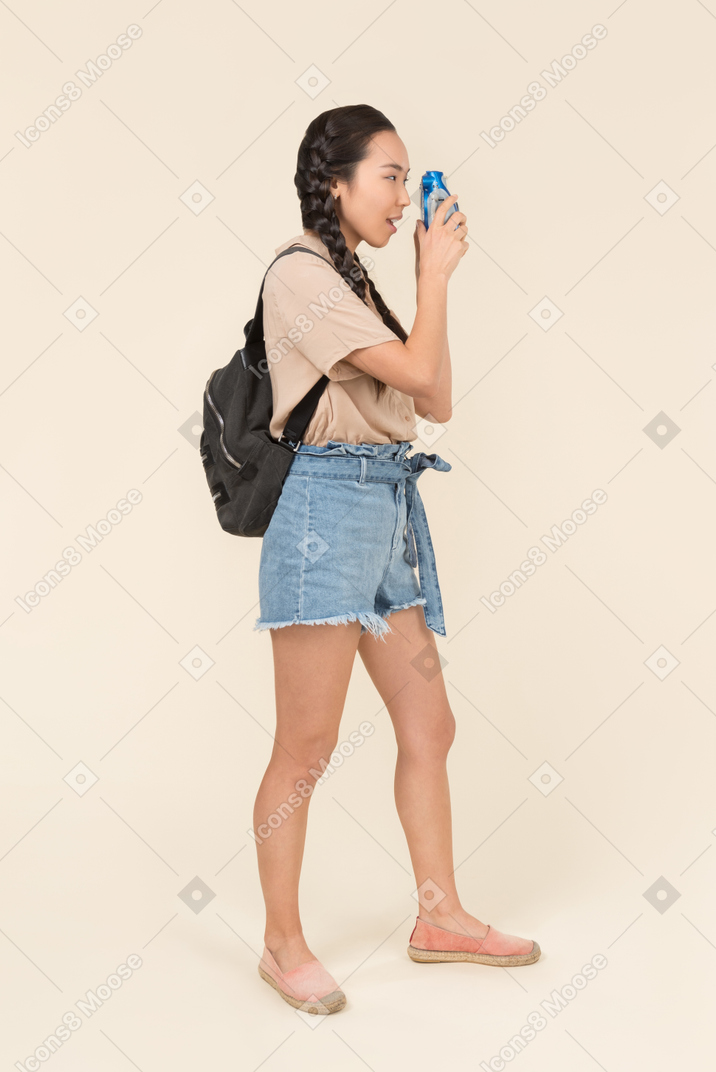 Young female tourist girl making a photo with blue camera