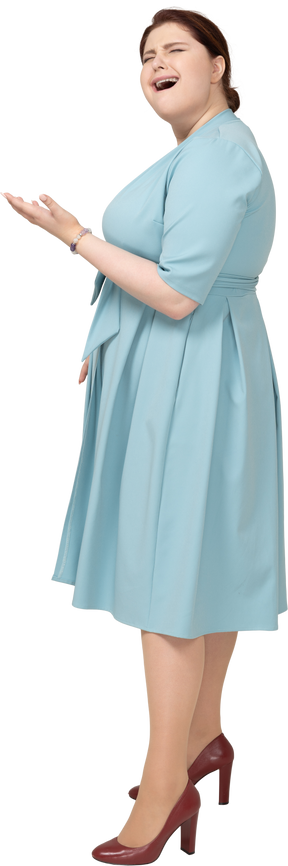 Женщина в синем платье, зевая, вид сбоку