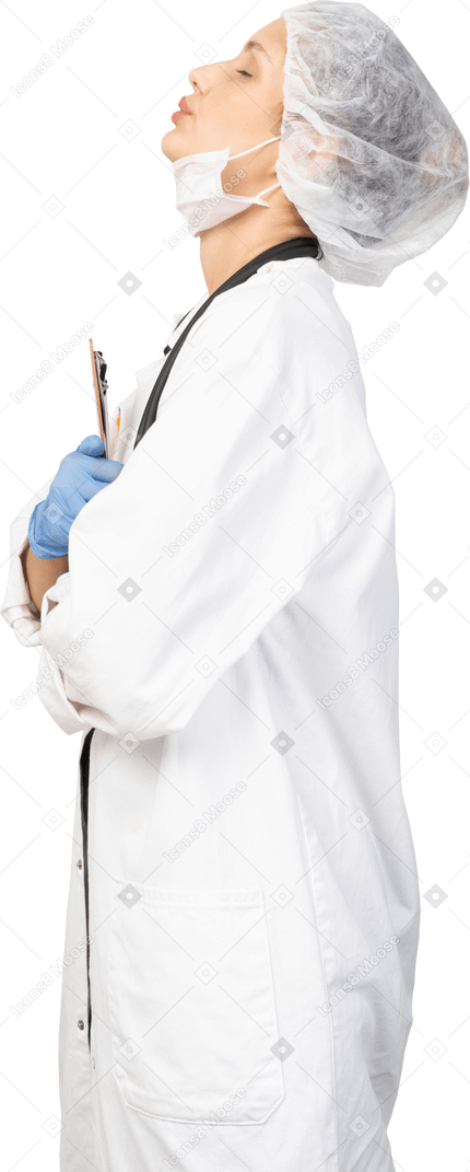 Vista lateral de una doctora joven soñolienta sosteniendo un lápiz y una tableta