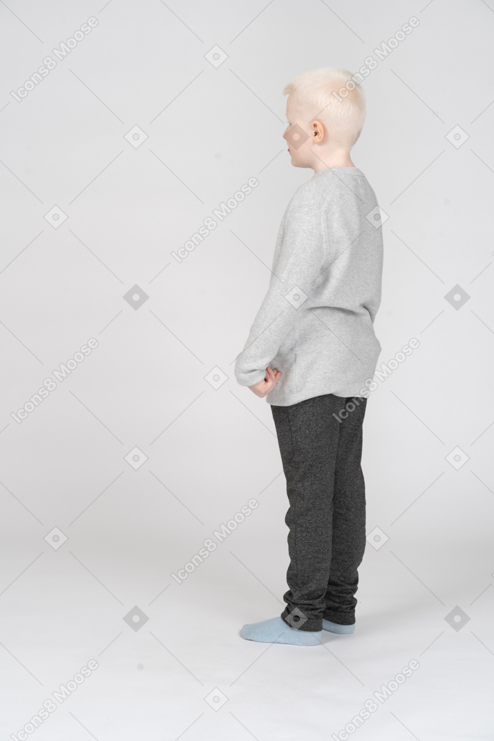 Back three-quarter view of a lonely kid boy in casual clothes