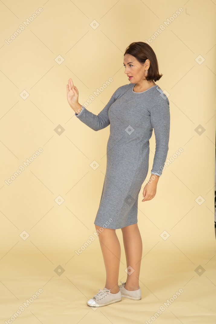 Vue latérale d'une femme en robe grise faisant des gestes