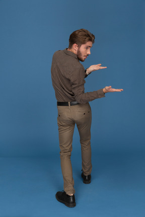 A slim young man turning backwards and showing his hands