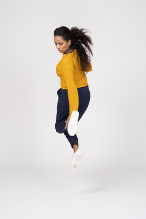 Retrovisor de uma garota com roupas casuais pulando e tentando tocar o pé