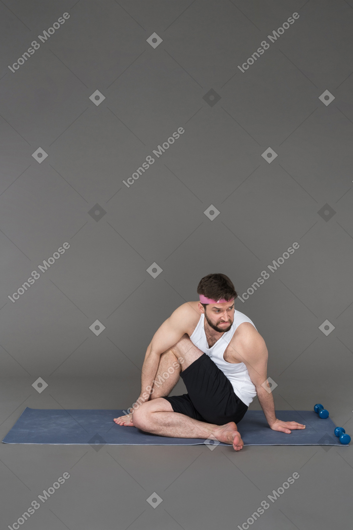 Sporty guy stretching after the workout