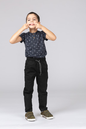 Vista frontal de un chico lindo poniendo los dedos en la boca y mostrando la lengua