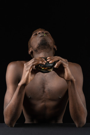 Vue de face d'un jeune homme afro dégustant un hamburger