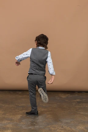 Rear view of a boy in grey suit walking