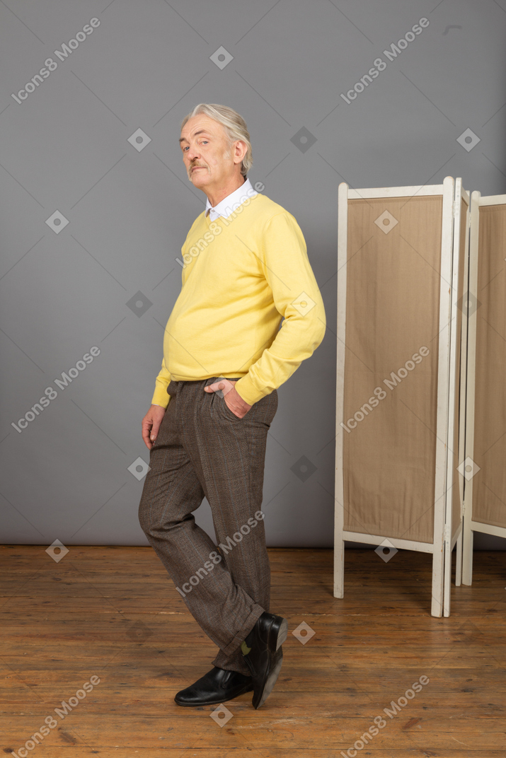Three-quarter view of an old man putting hand in pocket while looking at camera
