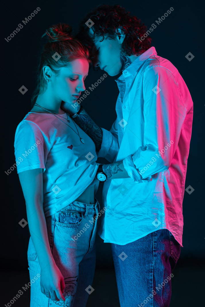 Young man and woman stand close to each other in the dark