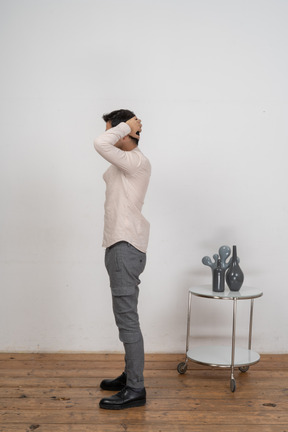 Vista lateral de um homem com roupas casuais, posando com as mãos atrás da cabeça