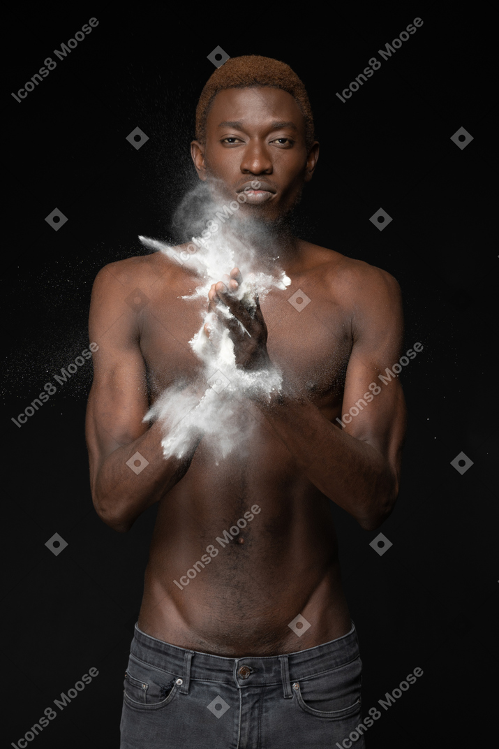 A young african male making a clap with a bursting flour